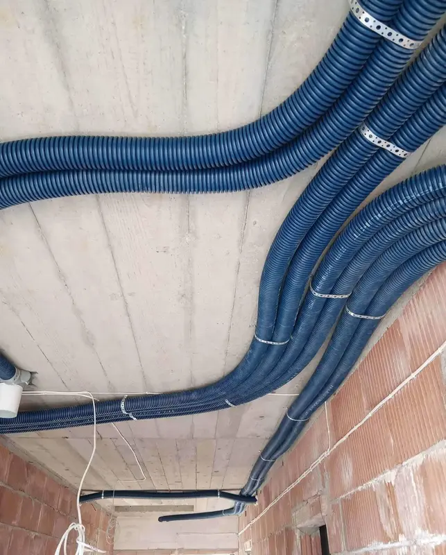 Podłużne niebeskie przewody od wentylacji rozprowadzone po całym pomieszczeniu