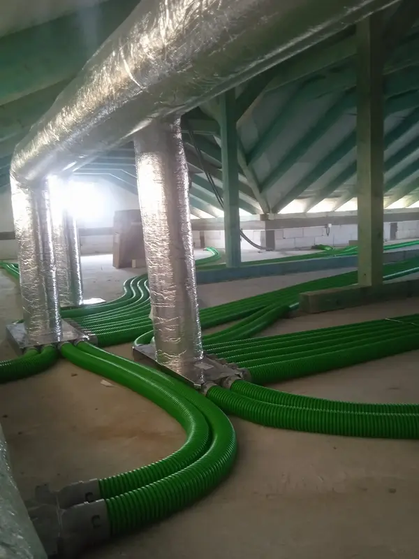 System rekuperacji składający się z zielonych, podłużnych rur zamontowany na poddaszu